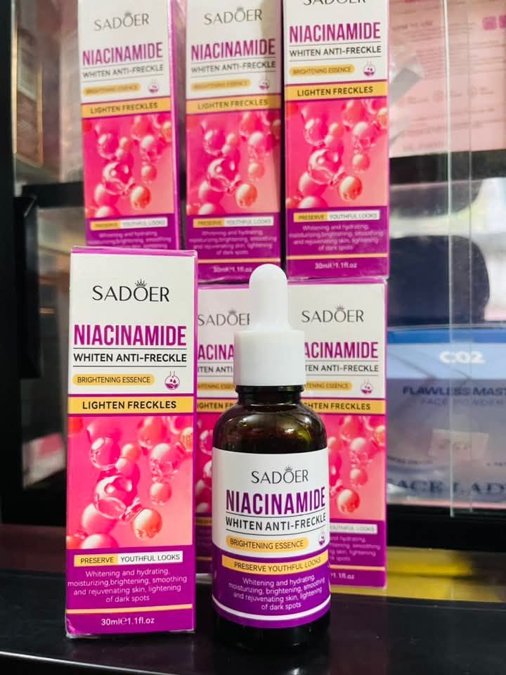 Sadoer Niacinamide skincare products on a black surface with blurred  anti frecklebackground