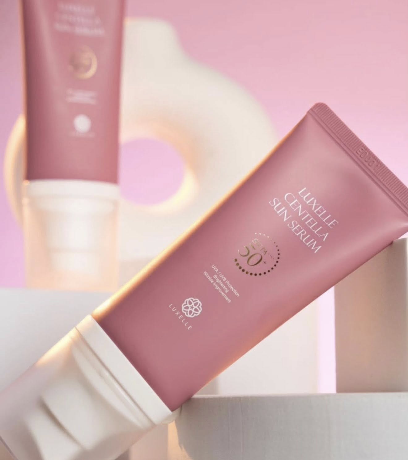 Pink skincare serum tube with brand name on a soft pink background