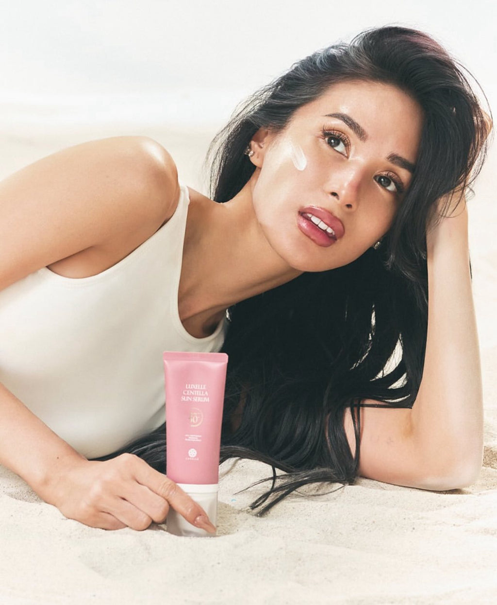 Woman holding a pink skincare product with a white background