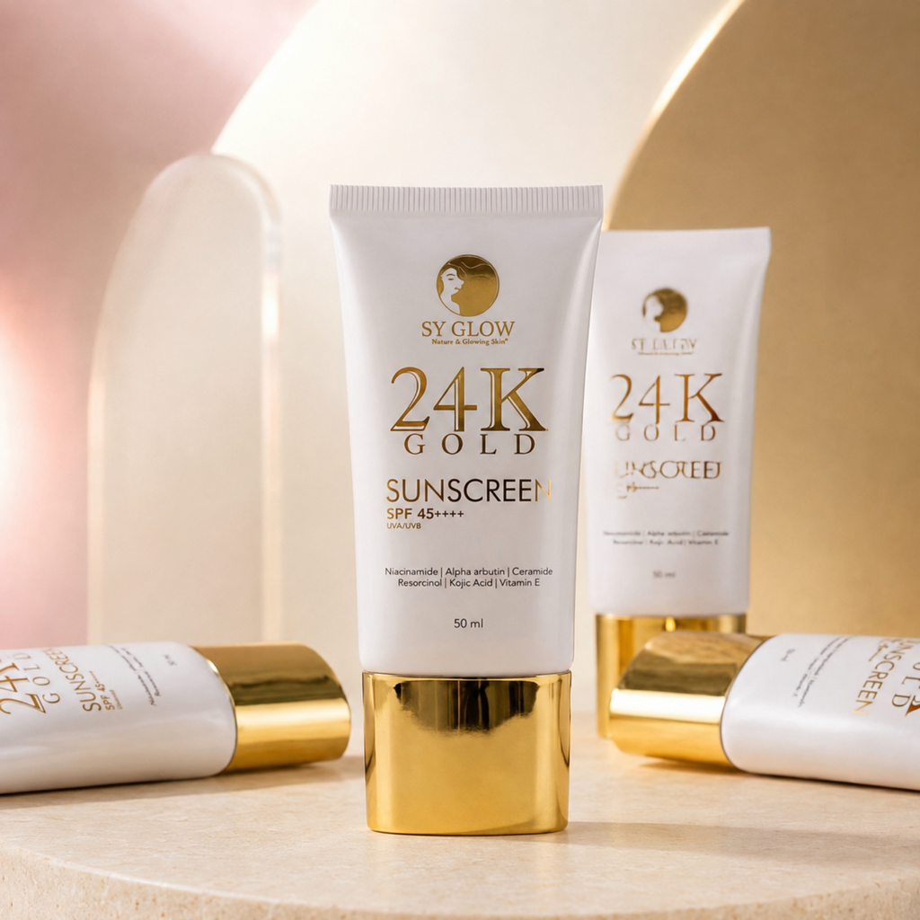 A 50 ml tube of SY GLOW 24K Gold Sunscreen SPF 45+ positioned centrally on a beige surface, flanked by two additional tubes lying down and one standing in the background, all set against a warm, abstract beige and gold studio backdrop.