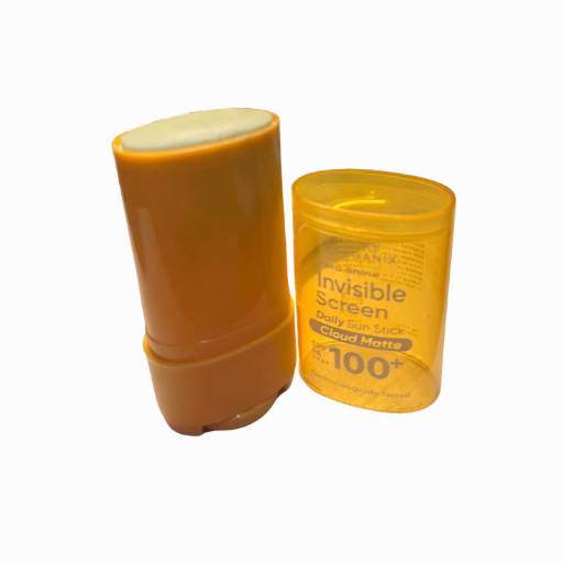 An orange-brown sunscreen stick next to its translucent yellow plastic container, labeled 'Invisible Screen Daily Sun Stick Cloud Matte SPF 100+'.