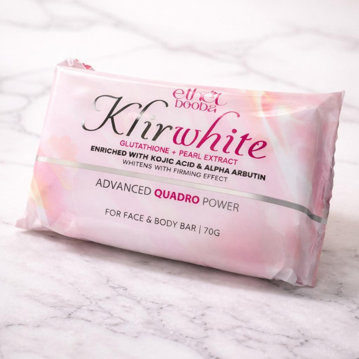 A pink foil-wrapped bar of body and face soap from Elixir Dooda, labeled 'Kirwhite Advanced Quadro Power', resting on a white marble surface.